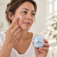 Illustrative scene of a woman applying pale blue Harvest & Hive balm to her cheek.